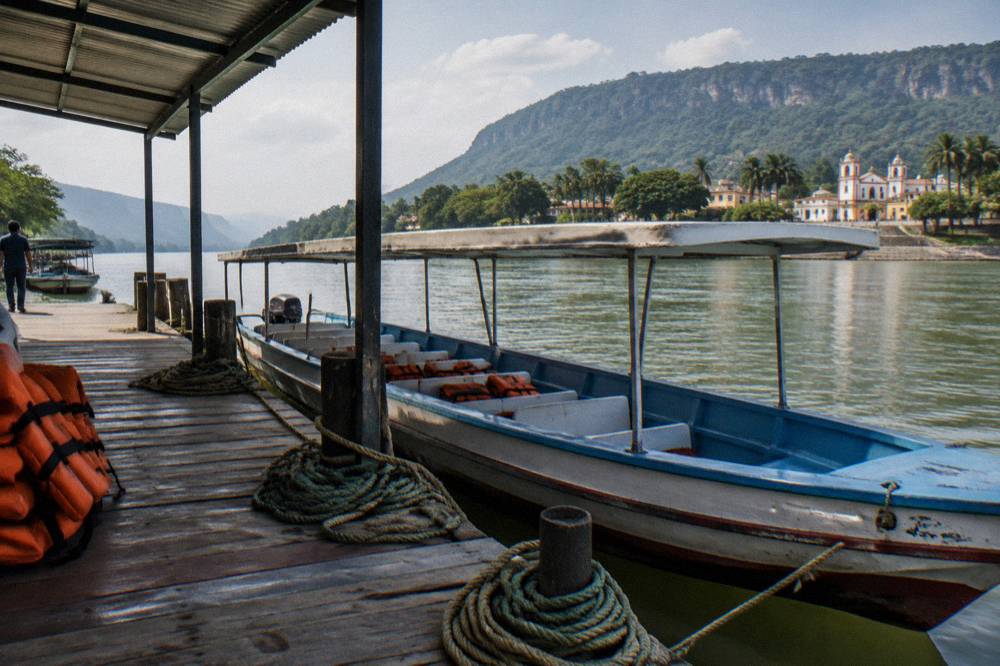Covered passenger lancha moored at a wooden dock on the Grijalva river before departure