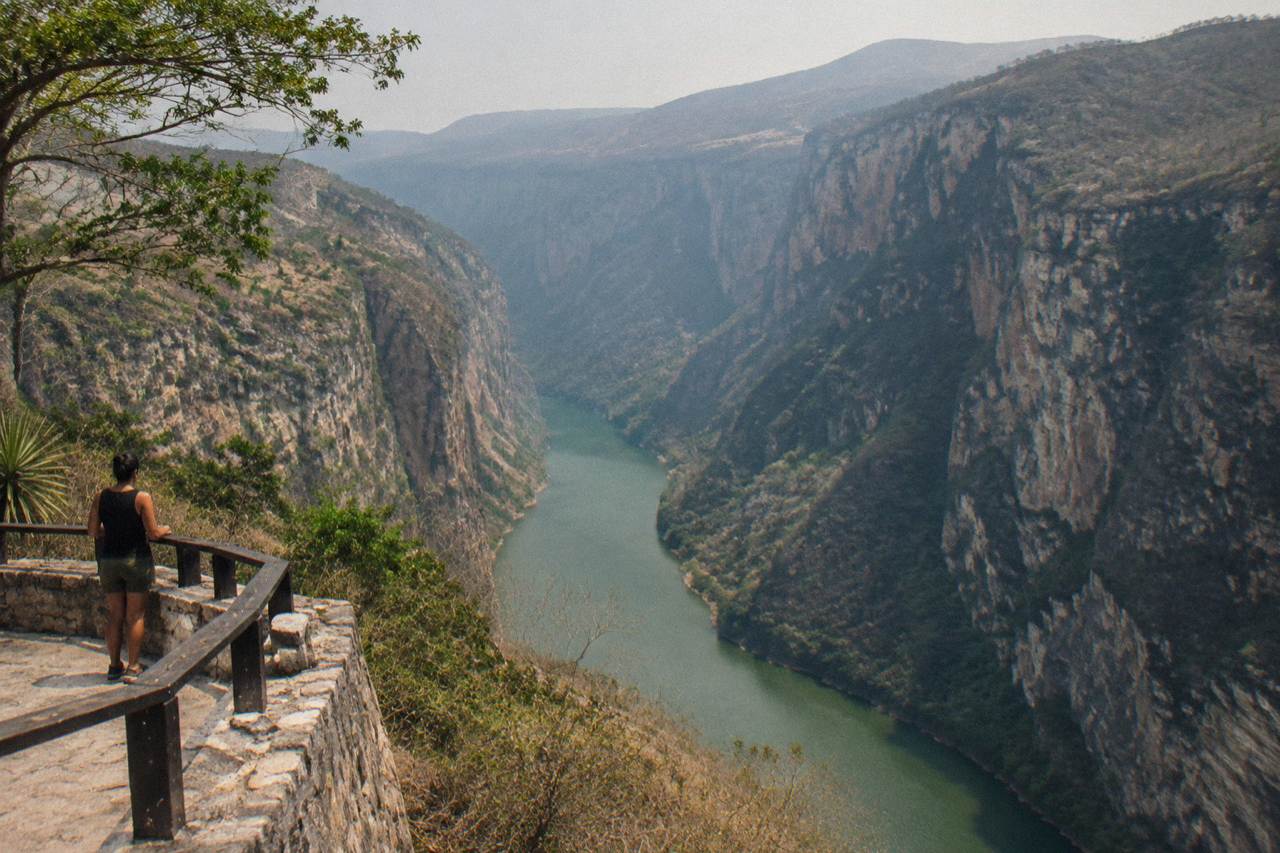 Tall limestone cliffs rising above a calm green river winding through a narrow canyon