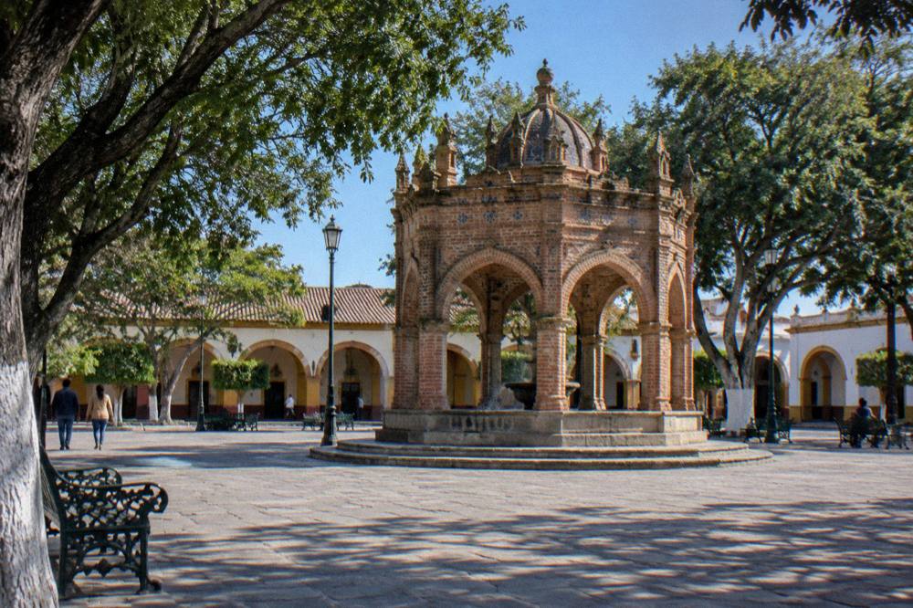 Colonial arcade and fountain square in a small Mexican town under a clear blue sky
