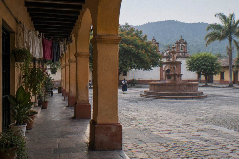 Colorful colonial buildings and a brick fountain around a plaza in a small Chiapas town