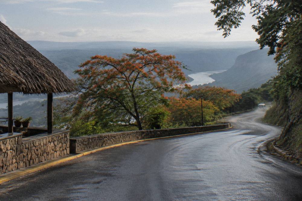 A van road winding down from green highlands toward the canyon valley in morning light