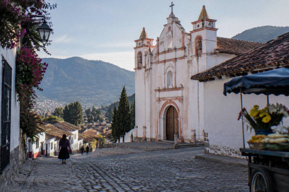 Whitewashed church with colorful facade beside a hillside village street