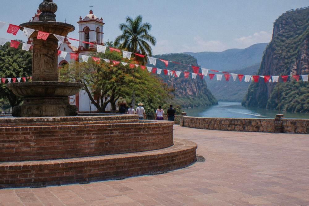 Crowded plaza of Chiapa de Corzo with festival decorations and the brick fountain