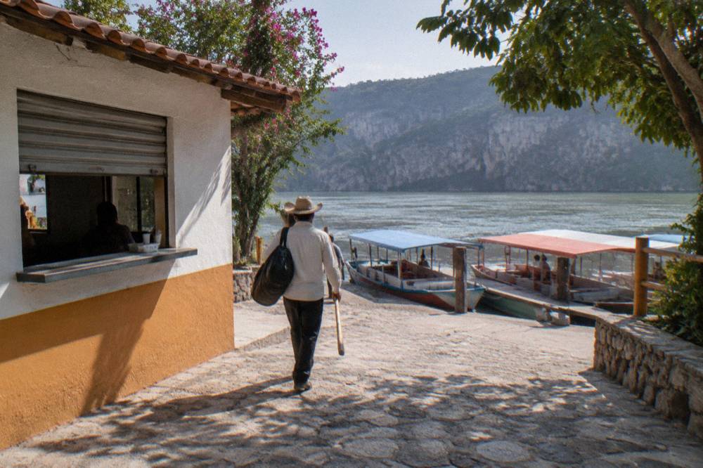 A riverside dock with small covered boats and a paved walkway in late morning light