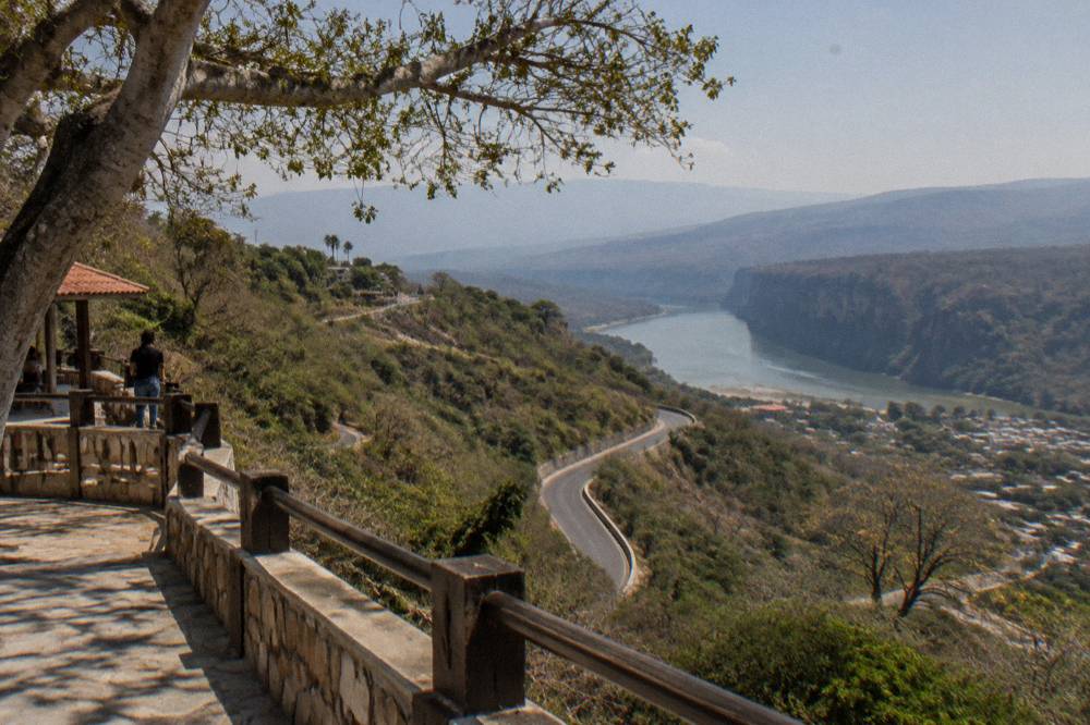 A winding highway cut through green hills heading toward distant mountain ridges
