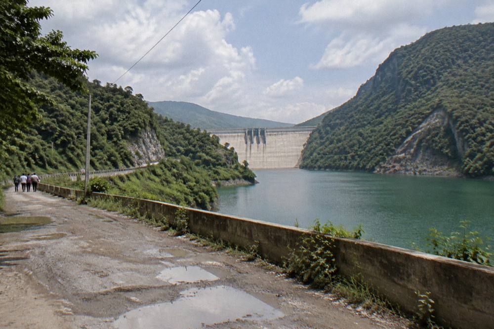 A wide river opening between forested canyon slopes under scattered clouds