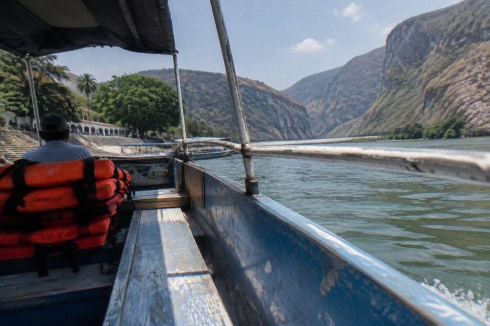 Row of orange life vests stacked on the seats of an open tourist boat at a river dock