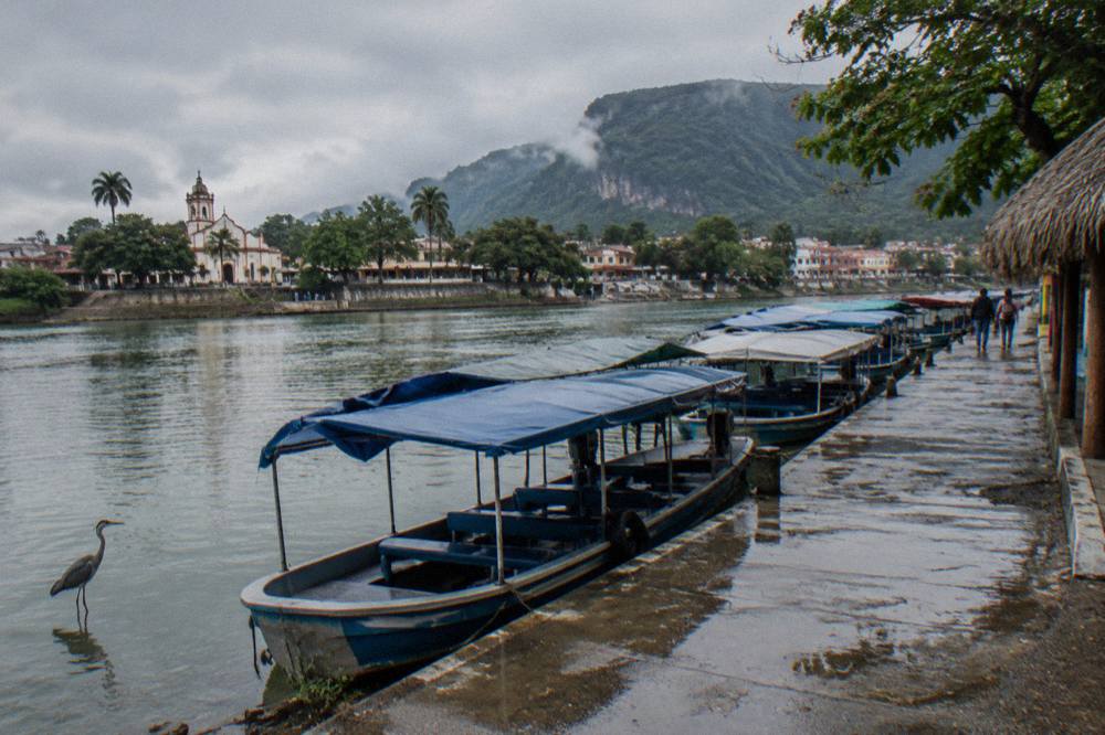 Row of covered tour boats moored at a river dock with the town waterfront behind