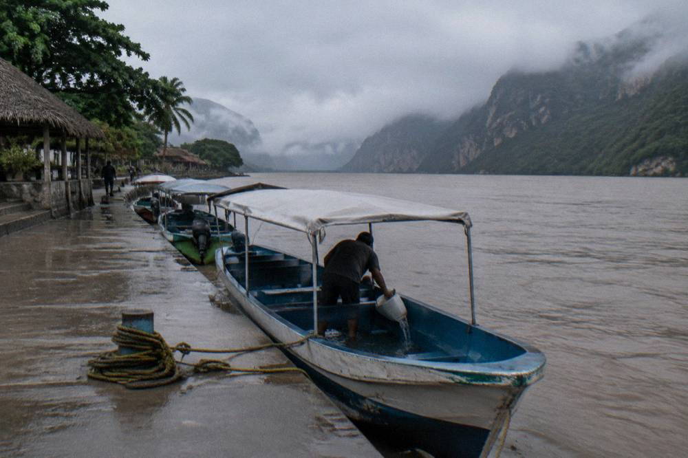 Small covered tour boats moored at a river dock under a grey sky before departure