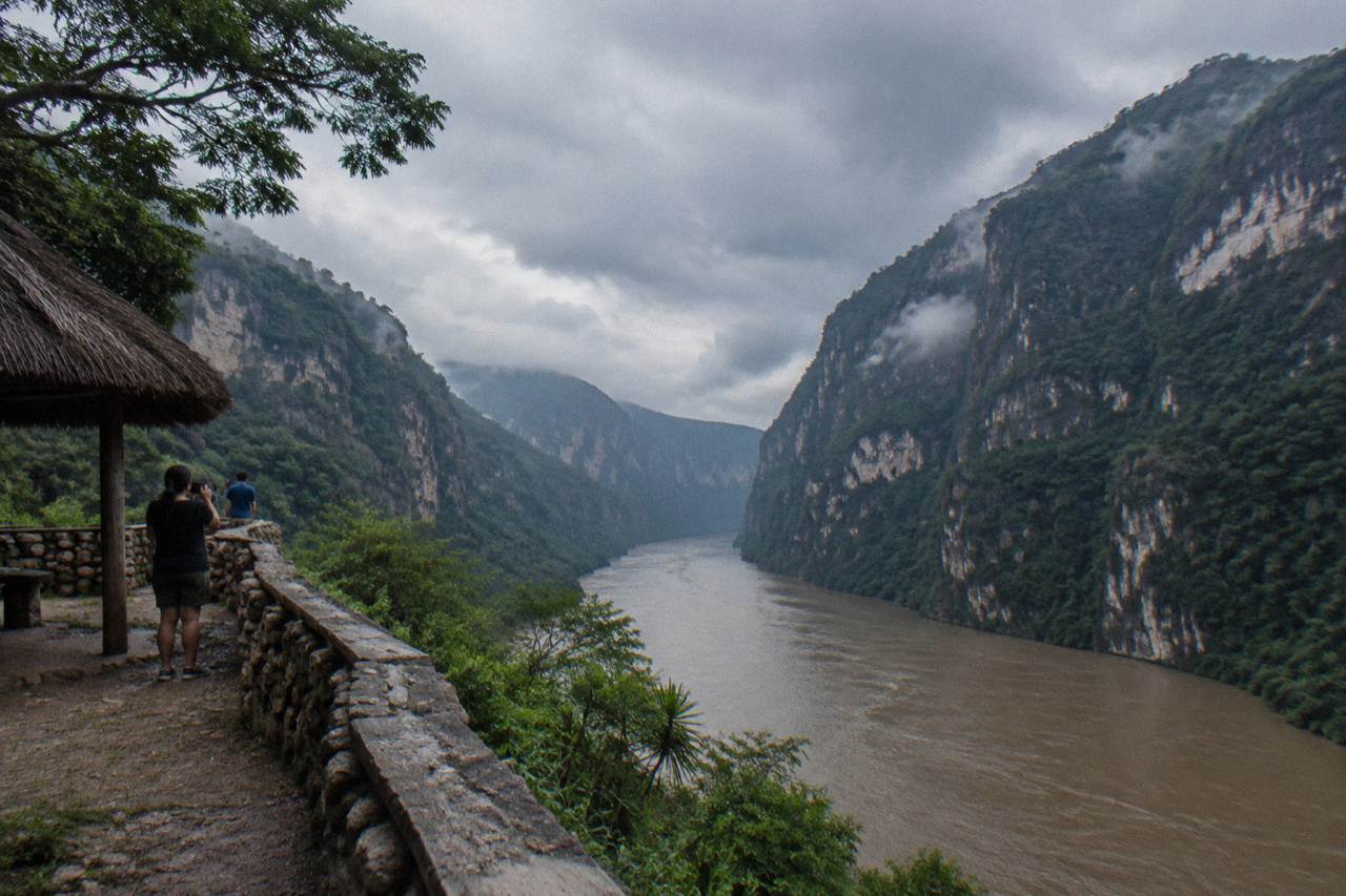 Rain clouds over the steep green walls of a tropical canyon with a wide river below