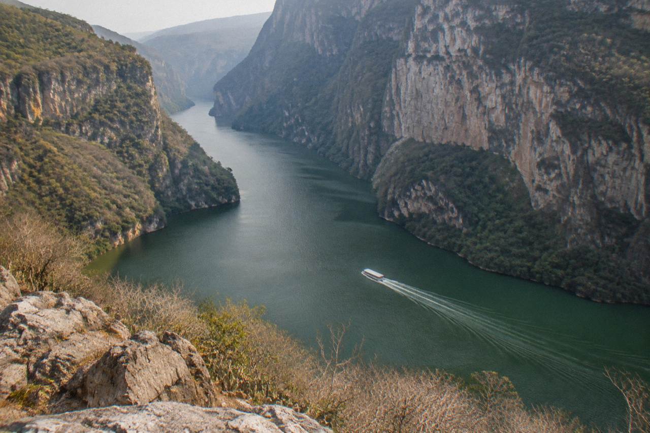 Viewpoint platform above a deep river canyon with tall cliff walls under a hazy sky