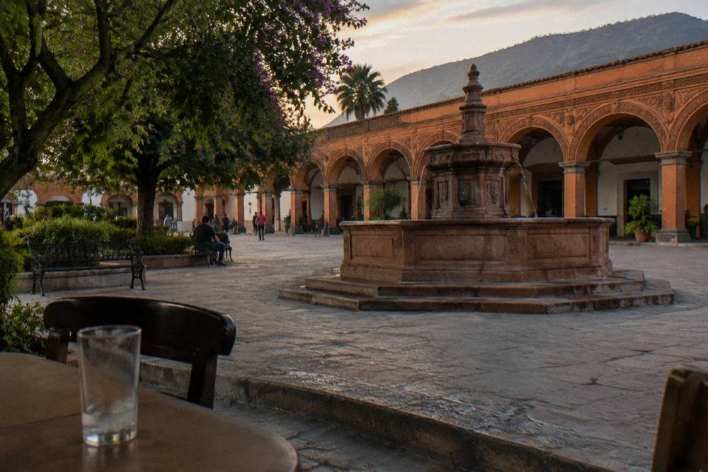 Colonial arcade and brick fountain on the main plaza of a southern Mexican town in warm afternoon light