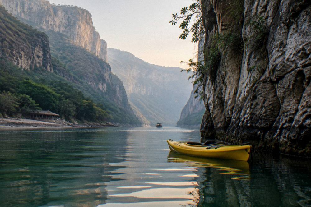 Kayak floating close to a tall rock face on a wide tropical river with reflections on the water
