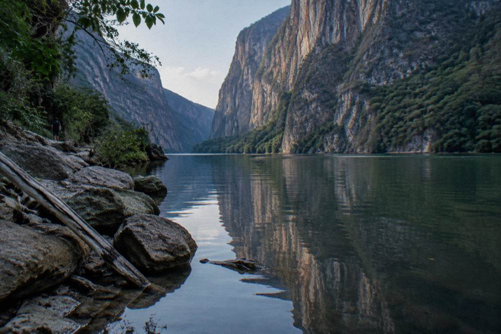 A narrow river passage between tall rock cliffs with still water below