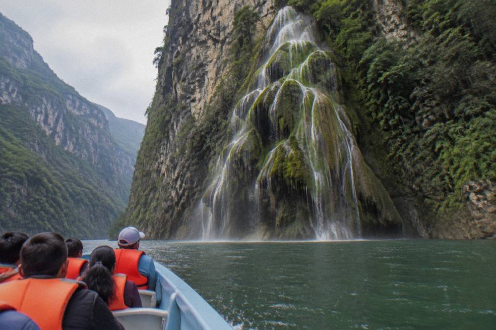 Speedboat crossing wide green water between tall canyon walls