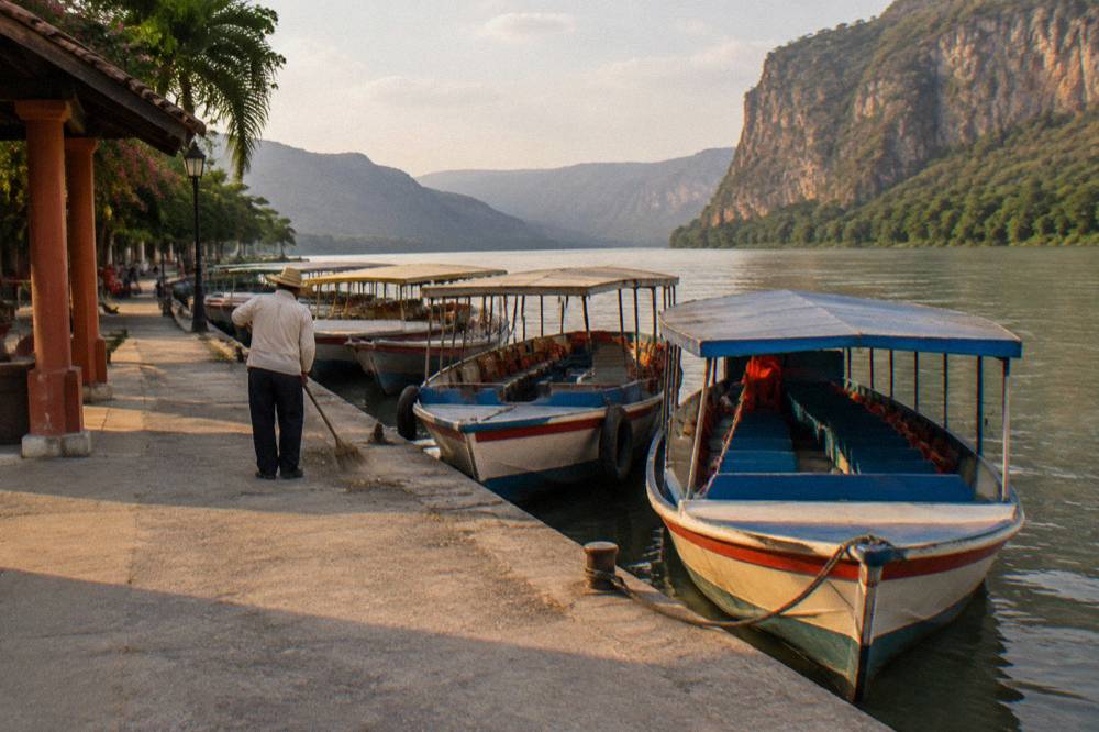 Covered boats moored at a river dock beneath a warm afternoon sky