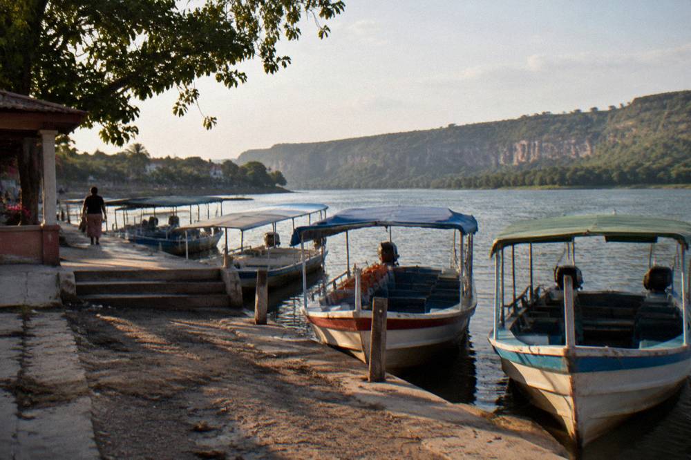 Small town waterfront dock with covered boats moored along a river bank