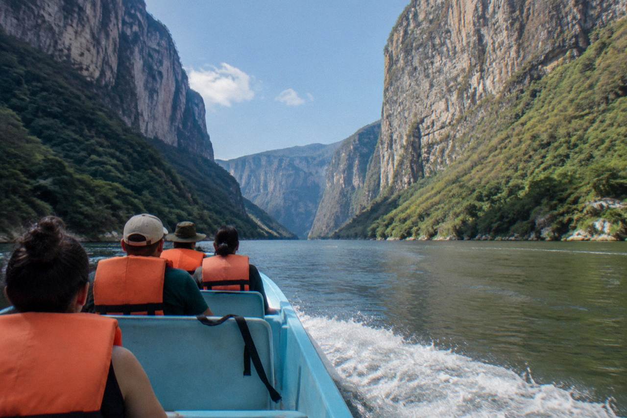 Boat on a wide river between tall cliff walls in Sumidero Canyon
