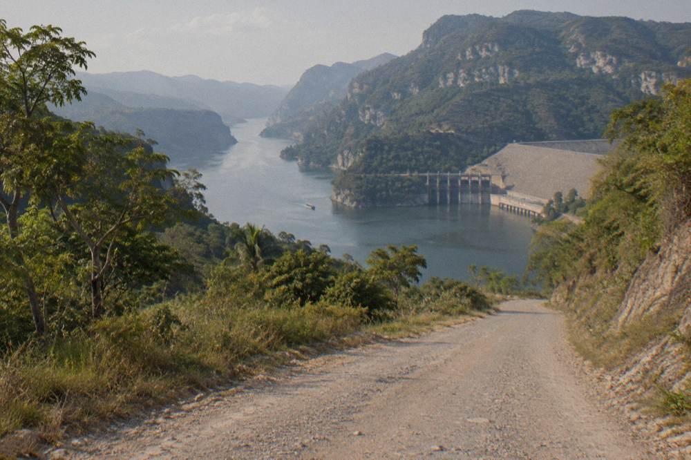 A winding road descending through green hills toward a river valley